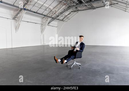 Geschäftsmann mit Tablet-PC auf dem Stuhl Stockfoto