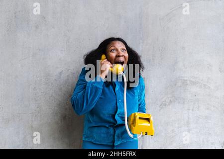 Schockierte Frau, die auf einem Telefon im Retro-Stil spricht Stockfoto