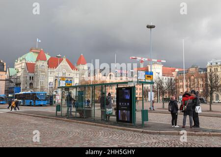 An einer Bushaltestelle auf dem Helsinki Railway Square warten Menschen auf den Bus.im November 2021 wurden in Finnland alle Covid-19-Beschränkungen aufgehoben. Die Leute laufen ohne Masken herum und alle öffentlichen Plätze waren offen. Stockfoto