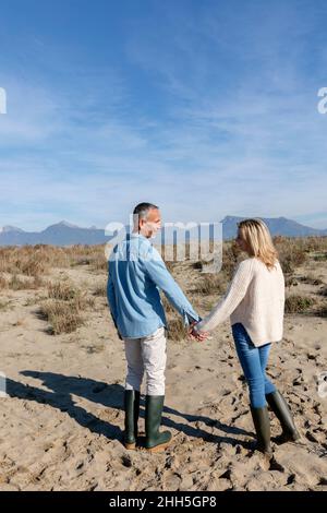 Mann und Frau halten die Hände, die an den Dünen stehen Stockfoto