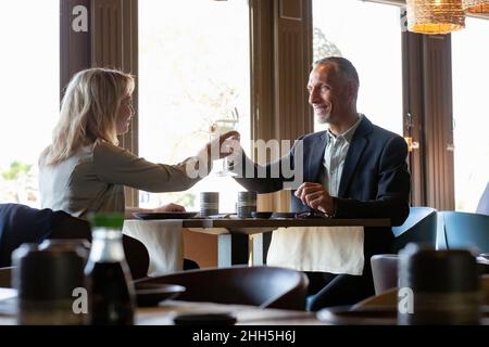 Ein Paar toaste Champagner-Gläser beim Mittagessen im Restaurant Stockfoto