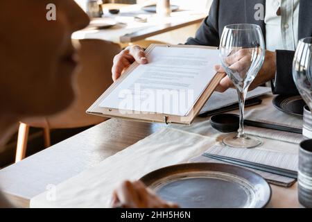 Geschäftsmann, der bei der Besprechung im Restaurant einen Vertrag vorführt Stockfoto