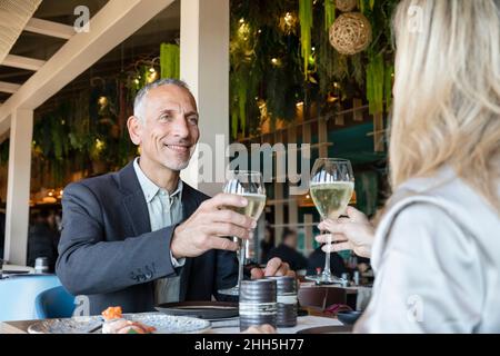 Ein Paar toaste Champagner-Gläser beim Mittagessen im Restaurant Stockfoto
