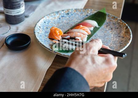 Mann hält Sushi auf Essstäbchen im Restaurant Stockfoto