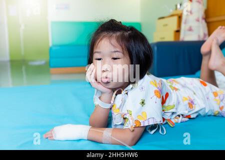 Krankheit Asian Kind im Krankenhaus eingeliefert, während Kochsalzlösung intravenös (IV) zur Hand. Unglückliches Mädchen, das sich traurig, gelangweilt fühlt, Kinderemotion. Konzept für Depressionen Stockfoto