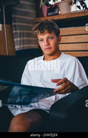 Hübscher junger Mann, der mit einem Magazin auf dem Sofa sitzt Stockfoto
