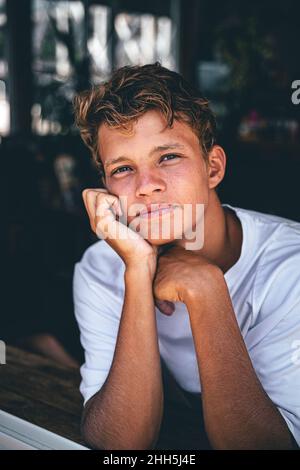 Junger Mann mit der Hand am Kinn am Cafefenster Stockfoto