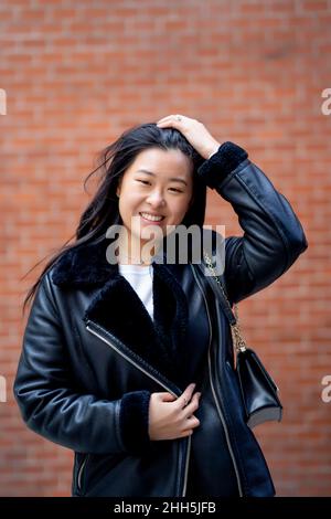 Lächelnde Frau in Jacke vor der Wand Stockfoto