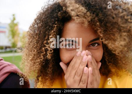 Junge Frau niest in den Händen Stockfoto