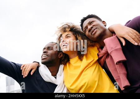 Fröhliche multirassische Freunde vor klarem Himmel Stockfoto