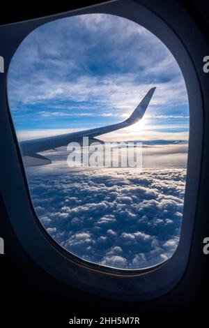 Dicke Wolken durch das Fenster des Flugzeugs, das darüber fliegt Stockfoto