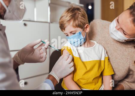 Mutter sieht den Sohn beim Arzt in der Mitte geimpft werden Stockfoto