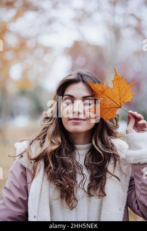 Frau mit Ahornblatt im Herbstpark Stockfoto