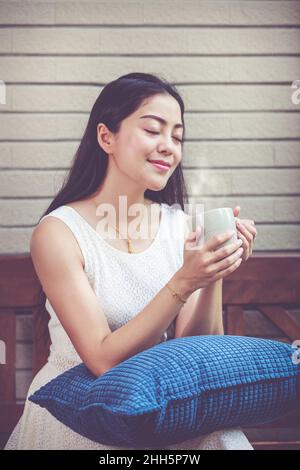 Lifestyle der schönen asiatischen Frau genießt frischen Kaffee am Morgen zu Hause. Glückliche Zeit der Stadt ​​life. Vintage-Ton. Stockfoto