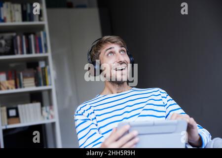 Überrascht Geschäftsmann mit Kopfhörern mit Tablet-PC im Home Office Stockfoto
