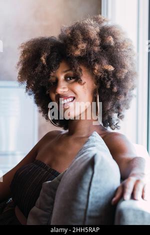Lächelnde junge Frau mit afro Frisur zu Hause Stockfoto