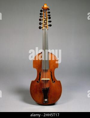 Viola d’Amore Ca. 1780 Joseph Gagliano Italienisch (Neapel) die Viola d'amore oder Viola 'der Liebe' ist ein Streichinstrument, das im 18. Jahrhundert große Popularität erlangte. Ein Großteil seiner Geschichte, einschließlich der Ableitung seines Namens, ist unbekannt. Es hat viele Eigenschaften der Gambenfamilie wie einen flachen Rücken, Rippen, die mit der Oberseite und dem Rücken bündig sind, und eine Rosette zusätzlich zu den Schalllöchern. Doch wie eine Geige wird sie beim Spielen unfrettiert und unter dem Kinn gehalten. Viola d'amore haben in der Regel sieben Saiten, obwohl Instrumente mit anderen Saitenzahlen nicht ungewöhnlich sind. P Stockfoto