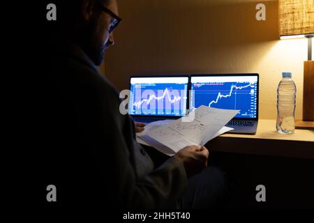 Börsenmakler, der Dokumente analysiert, die Kryptowährung handeln und im Home Office arbeiten Stockfoto