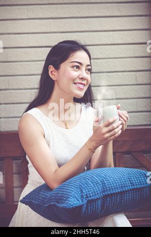 Lifestyle der schönen asiatischen Frau genießt frischen Kaffee am Morgen zu Hause. Glückliche Zeit der Stadt ​​life. Vintage-Ton. Stockfoto