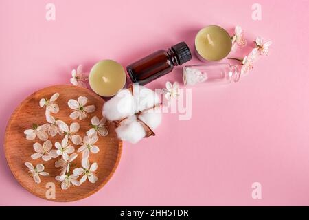 Konzept für Hautpflege, Spa und Aromatherapie. Naturkosmetikprodukte auf rosa Hintergrund. Duftkerzen und Blumen für Entspannung und Yoga. Platz für Stockfoto