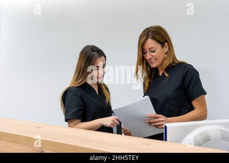 Lächelnder Gynäkologe, der in der Klinik mit einem Kollegen über ein Dokument spricht Stockfoto