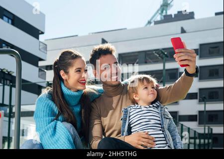 Lächelnder Vater nimmt Selfie mit der Familie auf dem Smartphone Stockfoto