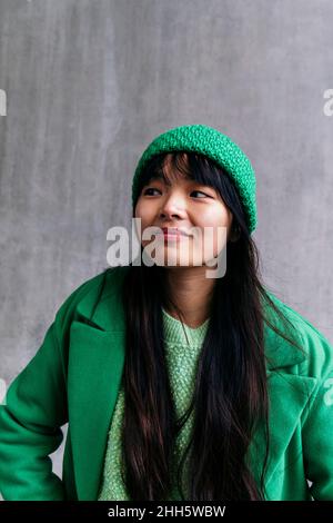 Junge Frau trägt grünen Wintermantel und Strickmütze Stockfoto