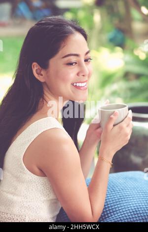 Lifestyle der schönen asiatischen Frau genießt frischen Kaffee am Morgen zu Hause. Glückliche Zeit des Stadtlebens. Vintage-Ton. Stockfoto