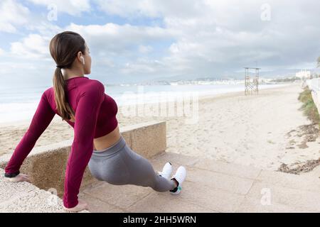Athletische Frau beim Push-up auf der Treppe am Strand Stockfoto