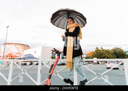 Teenager-Mädchen mit Regenschirm auf Geländer stehen Stockfoto