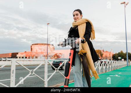 Teenager, der vor dem Himmel einen elektrischen Roller fährt Stockfoto