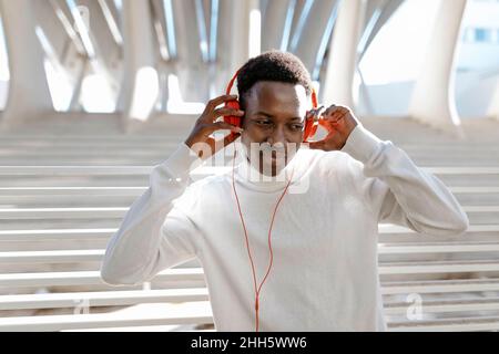 Junger Mann, der Musik über Kopfhörer hört Stockfoto