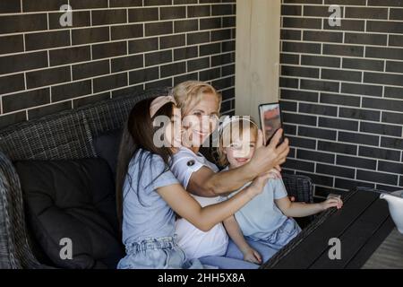 Lächelnde Großmutter beim Selfie mit Enkelinnen auf dem Smartphone Stockfoto