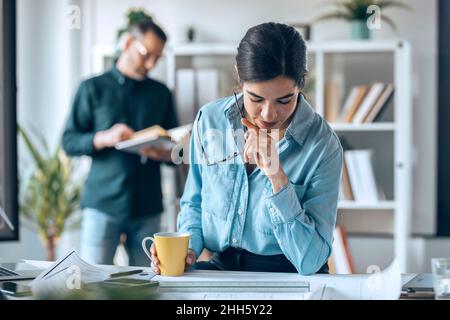 Architekt, der sich die Blaupause auf dem Schreibtisch in einem kleinen Büro ansieht Stockfoto