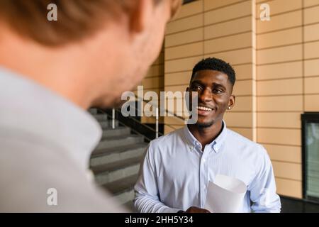 Lächelnder Mann im Gespräch mit einem Freund auf der Treppe Stockfoto