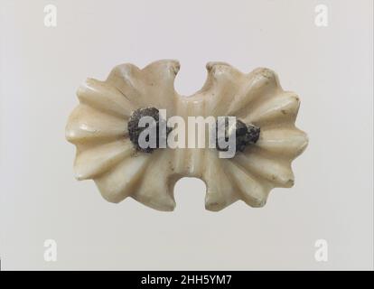 Ornament oder Knopf für Geschirr ca. 9th.–7th. Jahrhundert v. Chr. Assyrisch Dieses kleine Muschelstück wurde in einem Brunnen im Nordwest-Palast von Ashurnasirpal II. In Nimrud zusammen mit anderen ähnlichen Muschelornamenten gefunden, von denen sich einige auch in der Sammlung des Metropolitan Museums befinden (54.117.16, .17). Sie wurden vermutlich in den Brunnen geworfen, als der Palast geplündert wurde, in 614 B.C. und dann wieder zwei Jahre später. Sie können als Pferdezuführungen identifiziert werden und waren wahrscheinlich Teil eines Ledergeschirrs, das im Brunnenschlamm zerfallen ist. Pferde in den Reliefs des Palastes von Sargon II in Dur Sharrukin (Mo Stockfoto