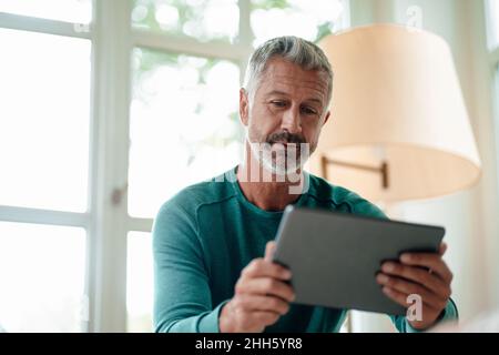 Reifer Mann, der zu Hause Tablet-PC verwendet Stockfoto