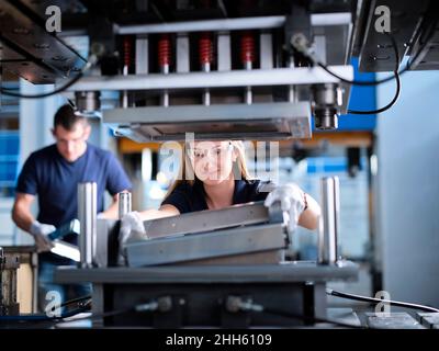 Ingenieur, der Metallrahmen in der Maschine im Werk justiert Stockfoto