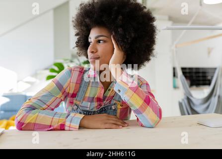 Kontemplative junge Frau, die zu Hause sitzt Stockfoto
