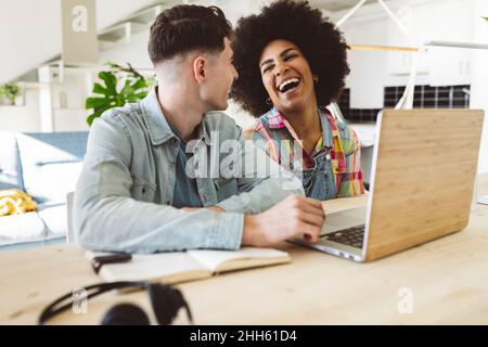 Glückliche Frau, die zu Hause mit einem Laptop von ihrem Freund lacht Stockfoto