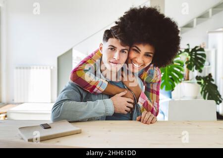 Glückliche Frau umarmt jungen Mann von hinten zu Hause Stockfoto