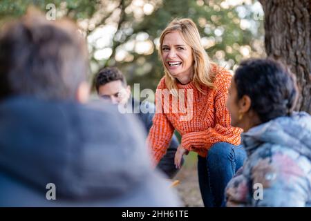 Fröhliche Frau mit Freunden im Park Stockfoto