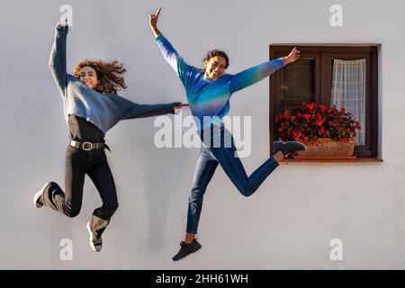 Fröhliche Freunde springen vor dem weißen Haus Stockfoto