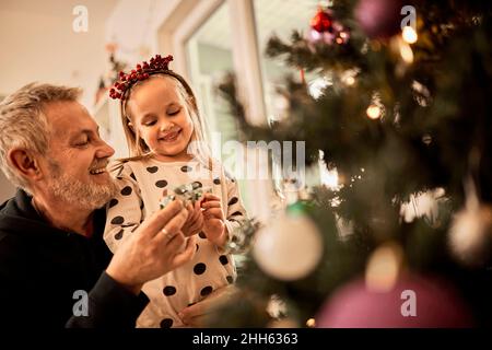 Großvater und Enkelin schmücken weihnachtsbaum zu Hause Stockfoto