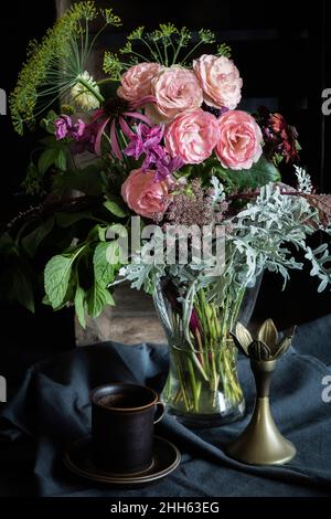 Studio-Aufnahme von Kaffeetasse und Strauß mit Mini Eden Rosen, Jahressigklaries (Salvia viridis), Spitze der Königin Annes (Daucus carota), schwarzäugigen Susans (Rudbeckia hirta), silbernem Ragwort (jacobaea maritima), Minze und Dill Stockfoto