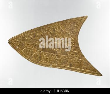 Plakette mit einem Greifvogel und geflügelten Bestien ca. 8th.–7th. Jahrhundert v. Chr. Iran Diese fein gearbeitete Tafel, die in der Technik des Repussés verziert ist, besteht aus einer Reihe von Verbindungsfragmenten. In der Mitte ist ein Greifvogel im Flug dargestellt, dessen Körper und Flügel von oben gesehen dargestellt sind. In seinen Krallen greift der Vogel zwei Kreaturen, während sich unter seinem Schnabel der Kopf eines bärtigen Mannes befindet. Ein Löwe mit offenem Maul konfrontiert den Vogel. Drei Bänder, die zusammengesetzte Kreaturen wie geflügelte Löwen und Bullen zeigen, schmücken den Umfang des Objekts. Ein Guillochmuster umrahmt das ganze Objekt. Fast dreieckig in s Stockfoto