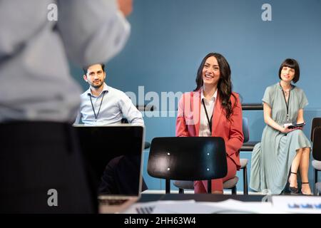 Lächelnde Geschäftsleute, die an Meetings am Arbeitsplatz teilnehmen Stockfoto