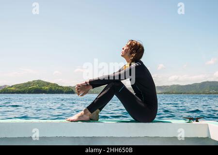 Junge Frau im Neoprenanzug am Strand von Del Coco an sonnigen Tagen Stockfoto