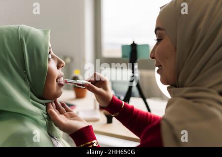 Frau, die zu Hause einen Freund mit Lippenstift anstiel Stockfoto