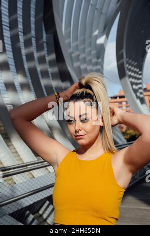 Nachdenkliche junge Frau, die Haare auf dem Steg bindet Stockfoto